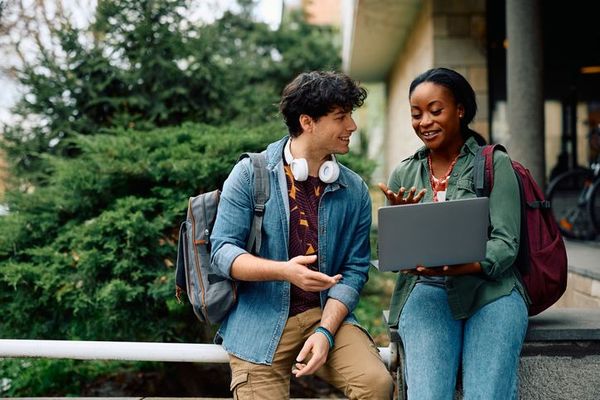 Two students on a laptop outdoor.